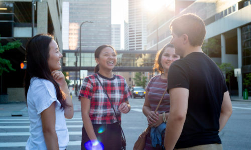 Group of students talking to each other on a sidewalk in downtown Minneapolis