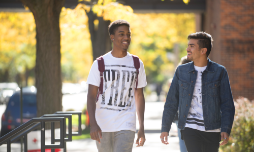 Two students walking next to each other outside in autumn.