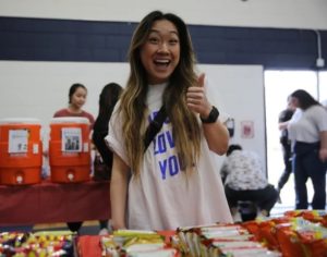 Student with thumbs up smiling at snack table