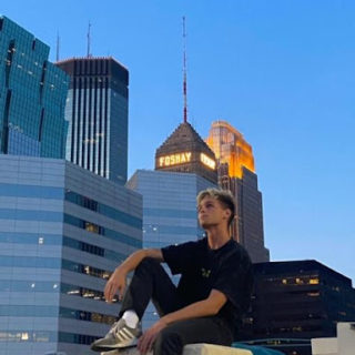 Thompson sits on a pylon and reflects in front of a city skyline